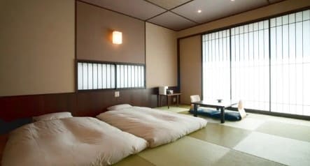 침구류와 작은 테이블 그리고 좌식의자가 타다미 위에 올려져 있다.