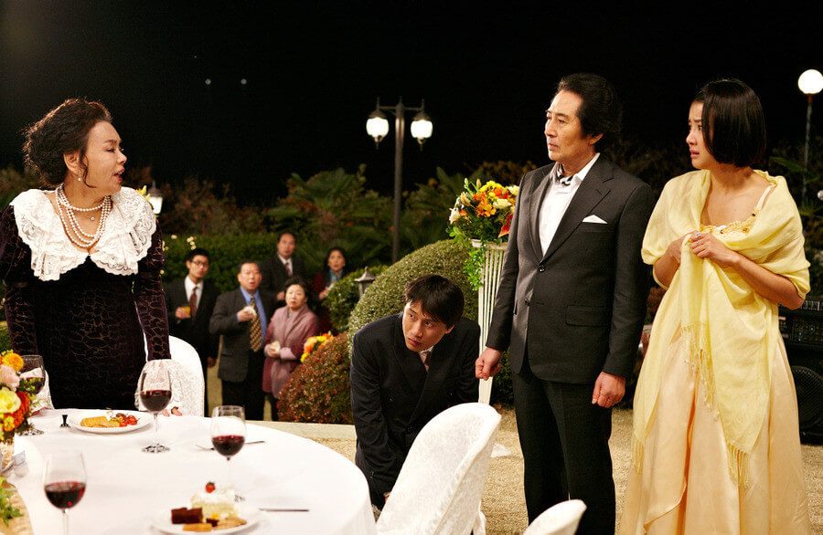 무릎 꿇고 있는 남자를 배경으로 싸우는 남자의 엄마와 여자의 아빠