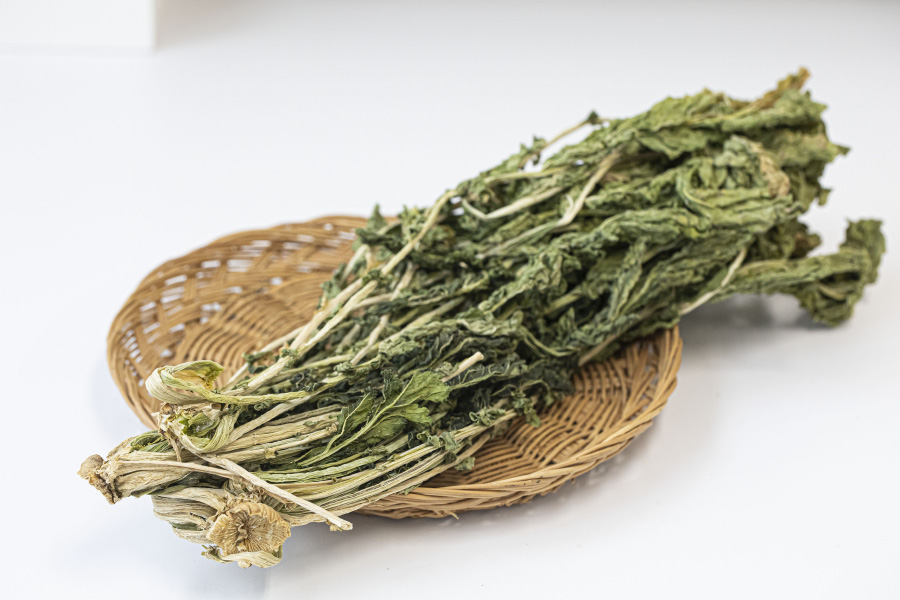 야생에서 채취를 한 무의 잎인 무청을 깨끗하게 세척하고 바싹 말린 것을 대나무 바구니에 담아 하얀 바닥 위에 놓아두고 찍은 사진