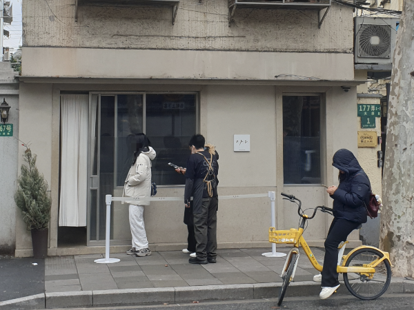 회색 건물 옵스 카페 앞에 줄을 선 사람과 자전거를 탄 사람