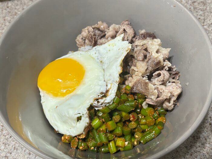 그릇에 고기, 계란후라이, 마늘쫑이 담긴 사진