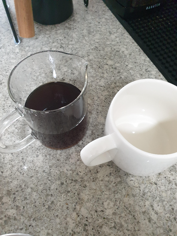 테이블 위에 추출된 커피가 들어있는 서버와 빈 컵이 올려져 있다.