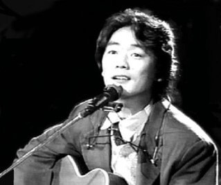 김광석-광야에서-김광석이-기타를-들고-마이크-앞에서-어딘가를-응시하고-있는-흑백-사진