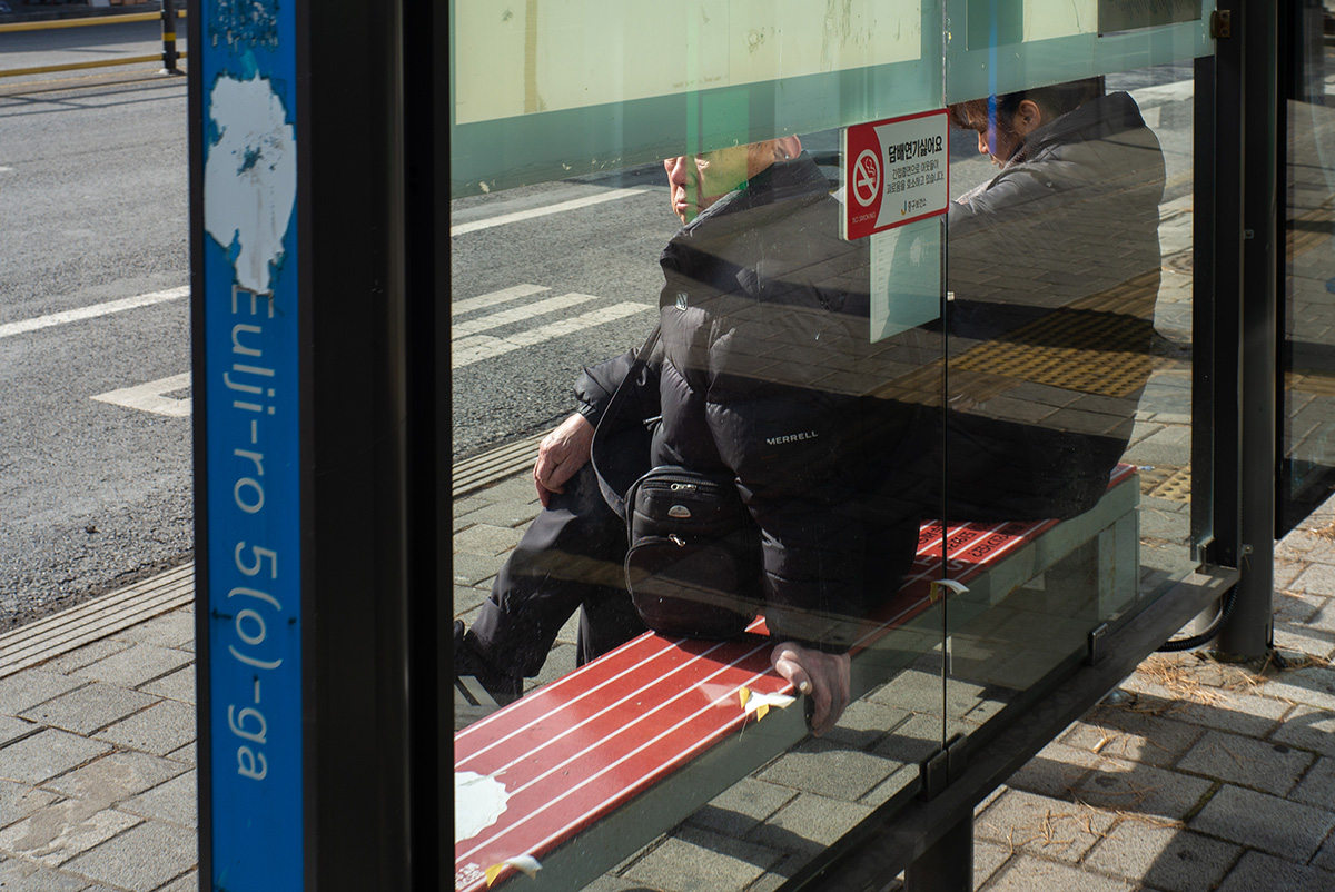 겨울 햇빛이 비치는 버스 정류장에서 앉아 쉬고 있는 노인의 모습, 라이카 M-P Typ 240의 자연스러운 색감으로 담은 거리 사진