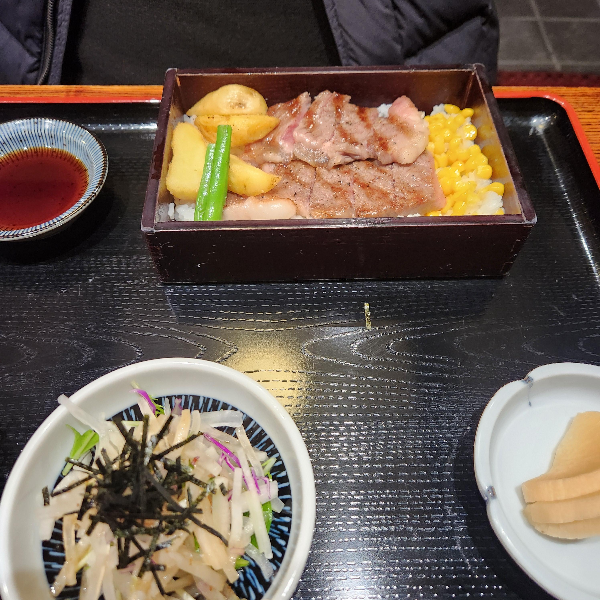 흑와규가 올라간 도시락. 간단한 밑반찬과 소스가 같이 보인다.