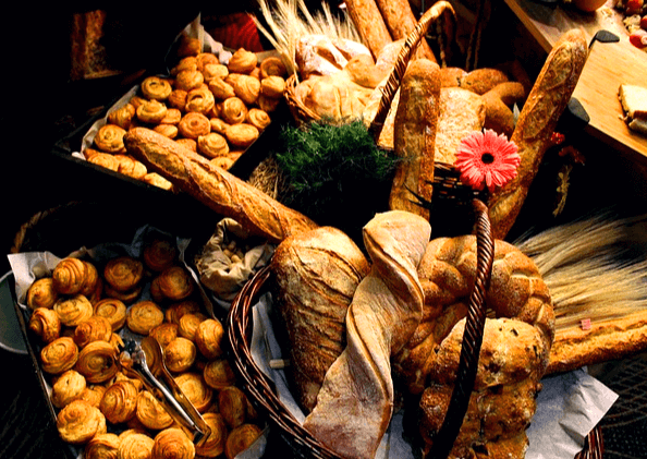 다양한 빵들이 많이 있다. 동그란 빵들, 기다란 바게트들, 커다란 빵덩이들이 가득하다.