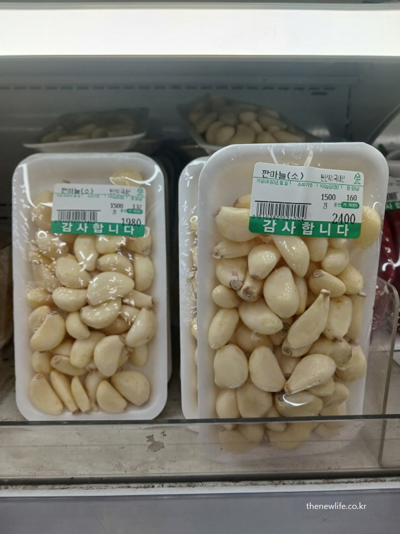 마트 진열대에 포장된 깐마늘 제품의 모습으로, 조리나 생식에 바로 사용할 수 있는 신선한 생마늘의 형태를 보여주는 사진