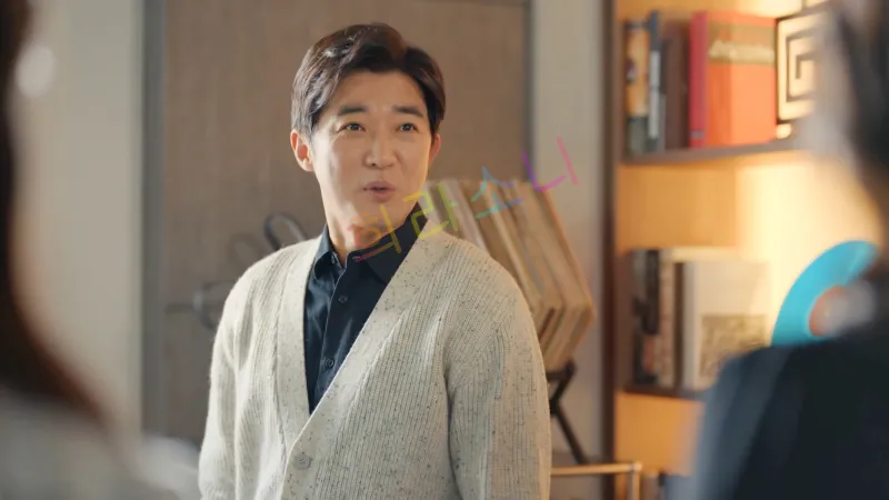 한동석(안재욱)의 모습. 그는 검은 셔츠 위에 베이지색 가디건을 걸치고 있으며&amp;#44; 짧고 단정한 갈색 머리를 하고 있다. 배경에는 책장과 장식품이 놓여 있다.