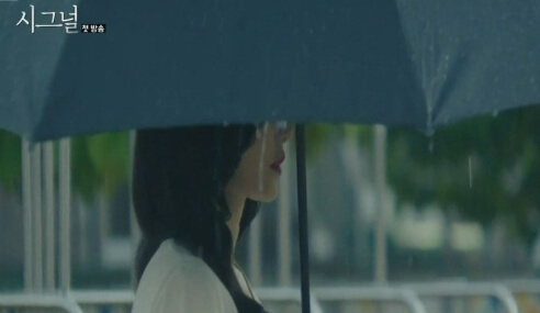 시그널 드라마 시즌1비 오는 날 파란 우산을 쓰고 조용히 서 있는 여성의 감성적인 옆모습, 흐릿한 배경 속 분위기 연출