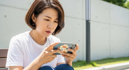 스마트폰으로 퍼즐 게임을 집중하며 하는 중년 여성