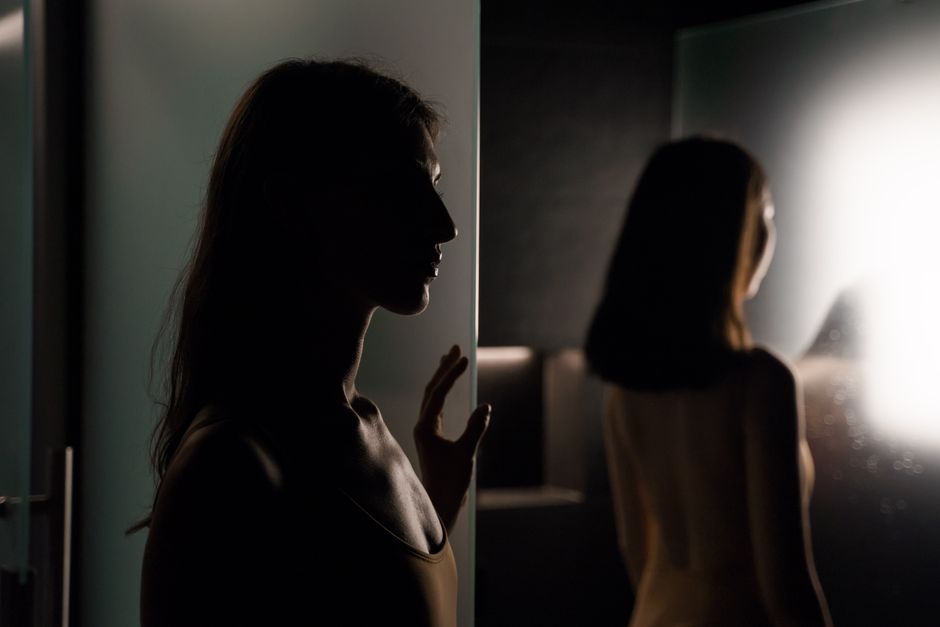 Artistic silhouette of a woman in a dimly lit spa, creating a moody atmosphere.