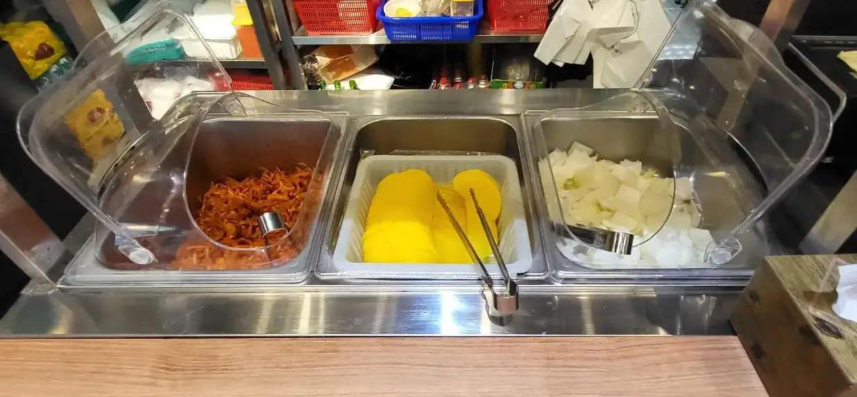 보배반점 -
3개의 큰 반찬통안 주황색 짜샤이, 노란색 단무지, 흰색 양파가 각각 가득 놓이고 그안 집게가 각각 담겨있는 이미지