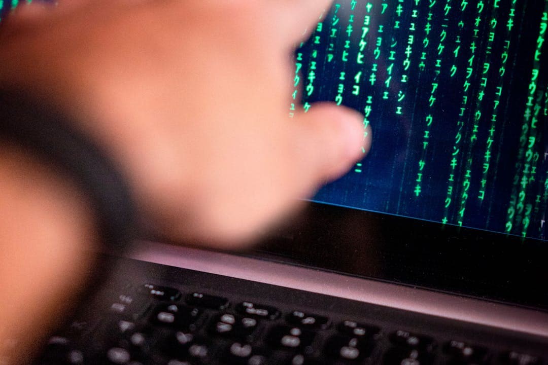 코드가 표시된 노트북 화면을 가리키는 손, 챗GPT 활용 장면