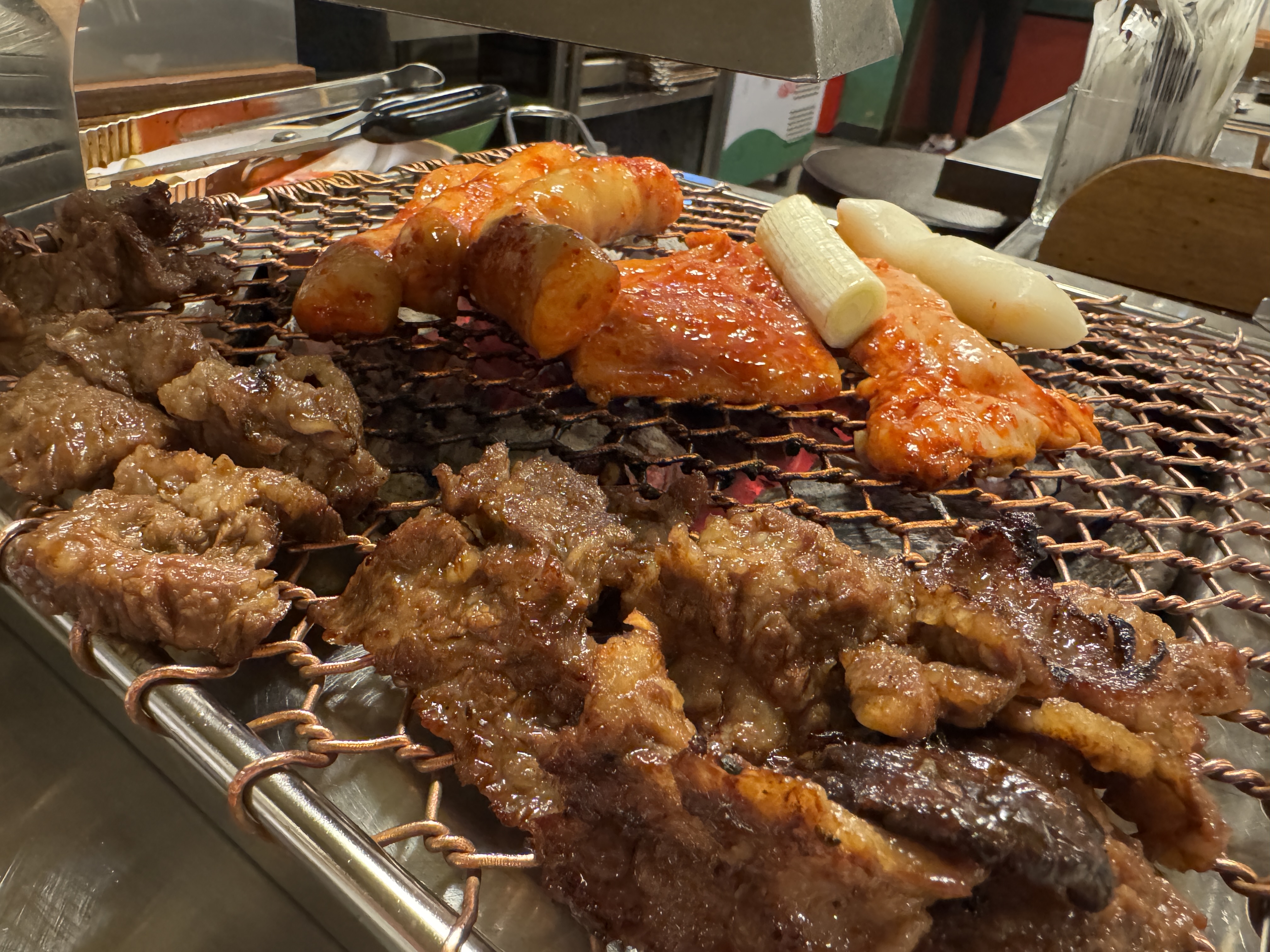 세광양대창 정자점 불판 위에서 마늘 소갈비살이 구워지고, 그 옆에 양념된 대창과 특양이 막 올려지는 장면. 불빛 아래 윤기가 흐르는 고기와 떡이 어우러져 식욕을 자극하는 모습