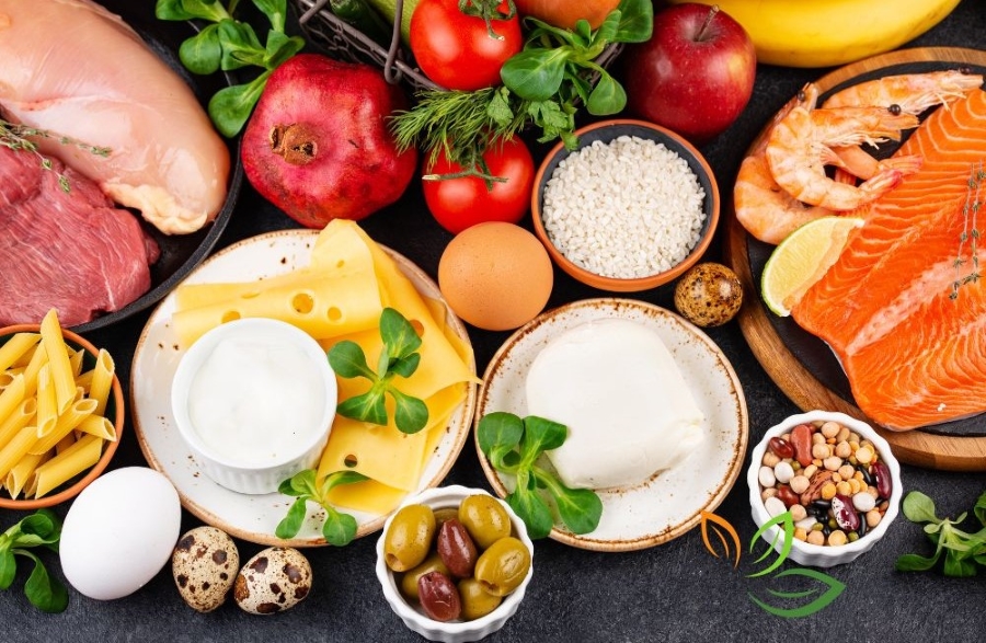 다양한 고단백 식품들이 어두운 배경에 배치된 모습 - 연어, 닭가슴살, 달걀, 치즈, 견과류, 토마토, 사과 등 VIA CANVA