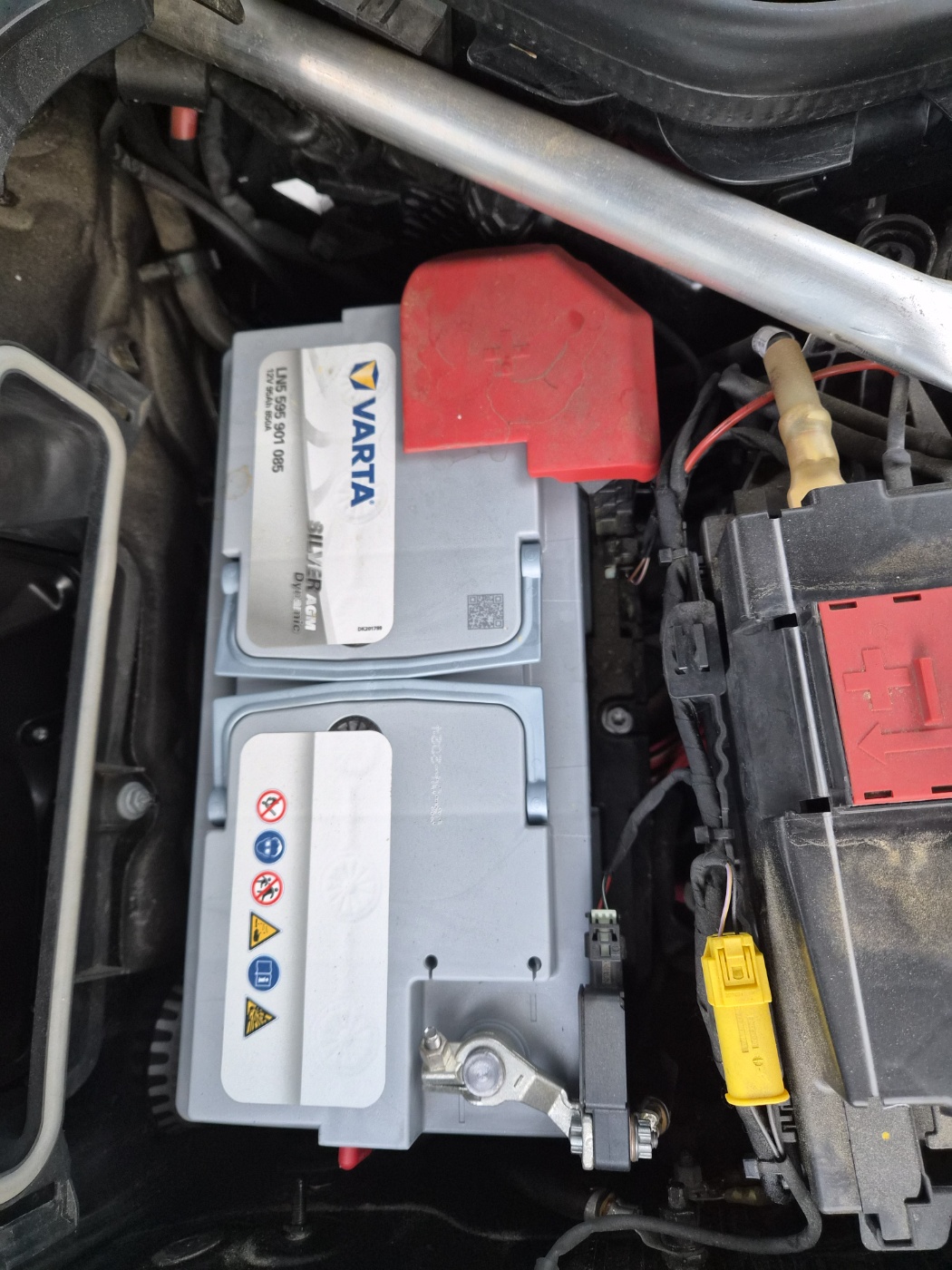 차량 보닛 내부에 장착된 메인 배터리 사진. VARTA 브랜드 배터리와 빨간색 플러스 단자 커버, 배터리 주변 배선이 확인됨.