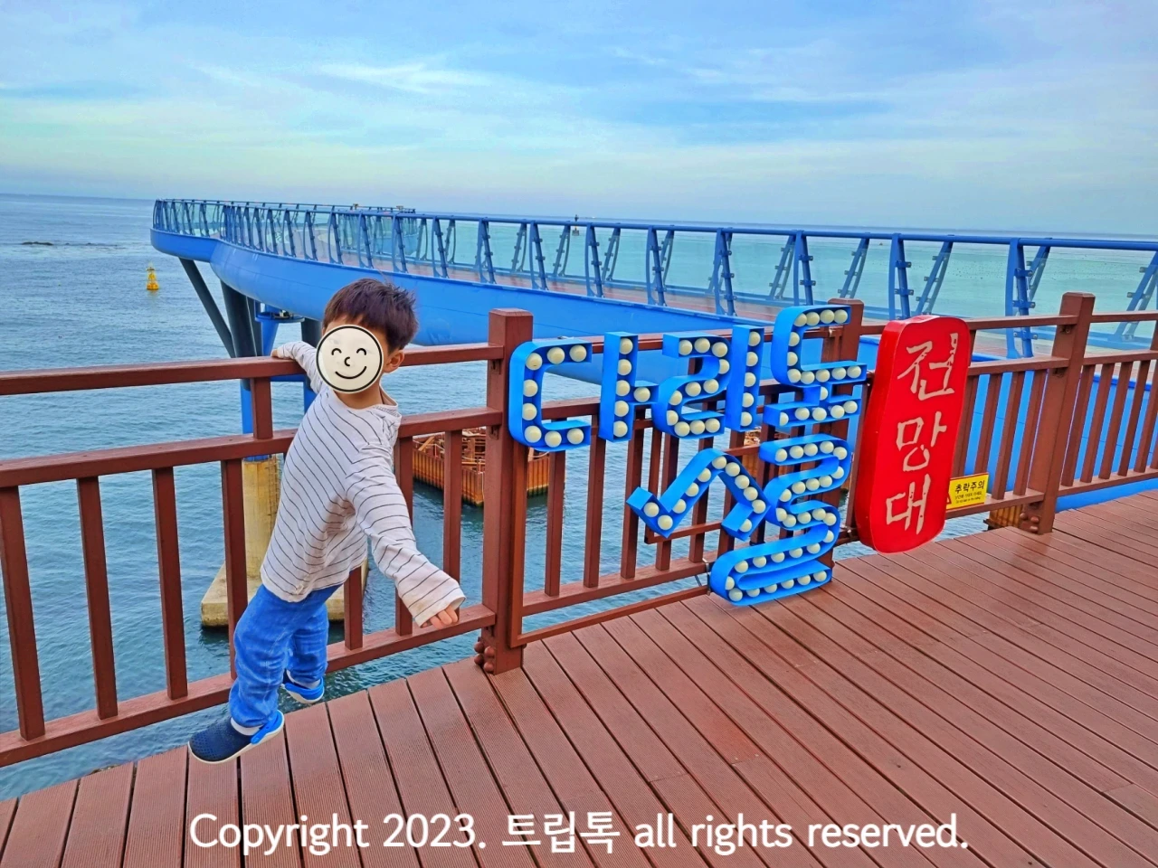 파란색 철골로 전망대가 바다위에 있고 난간에 파란색으로 다릿돌 전망대라고 적혀있다.