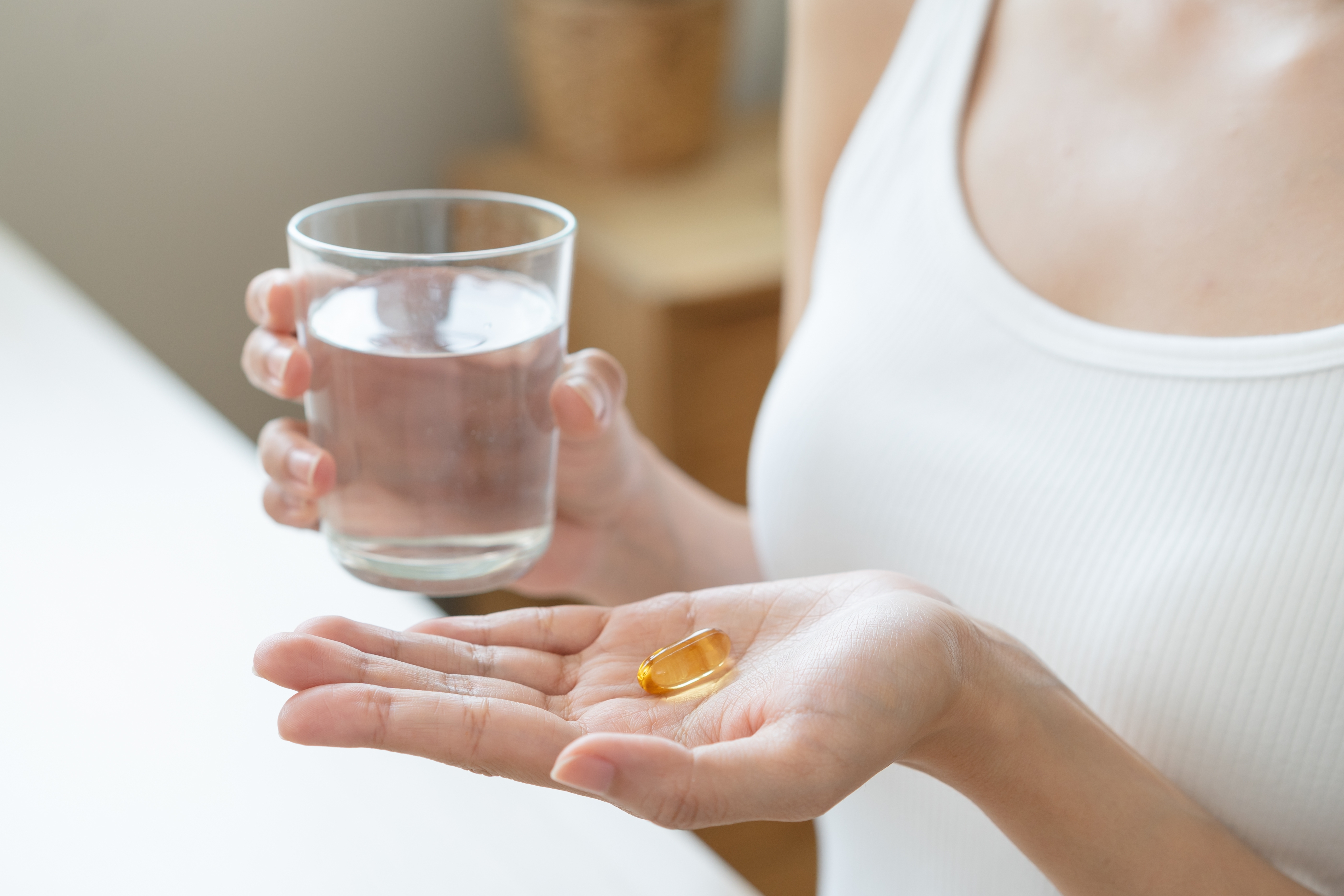 보조제를 물과 함께 섭취하려는 여성의 손과 유리컵