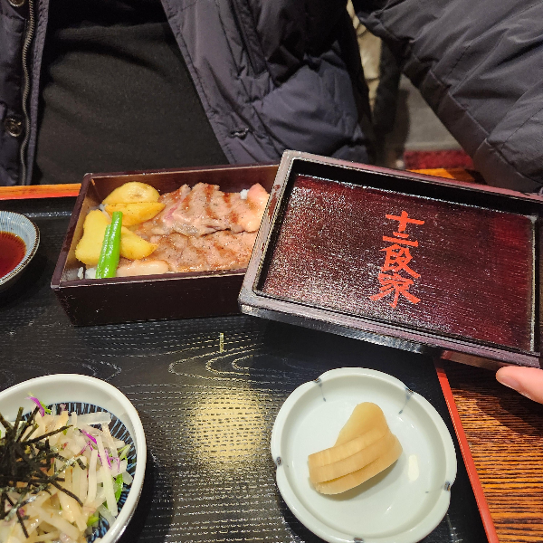 테이블 위에 도시락 정식이 있다. 도시락에는 흑와규 덮밥이 보인다.