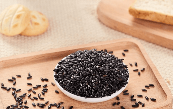 나무 쟁반 위에 흑미가 가득 담긴 하얀 그릇이 있고, 그 위에는 마가렛쿠키 2개가 있다.