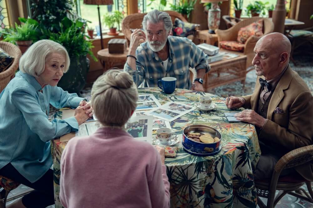 영화 목요일 살인 클럽 스틸컷 – 네 명의 주인공이 테이블에 둘러앉아 단서를 정리하는 장면