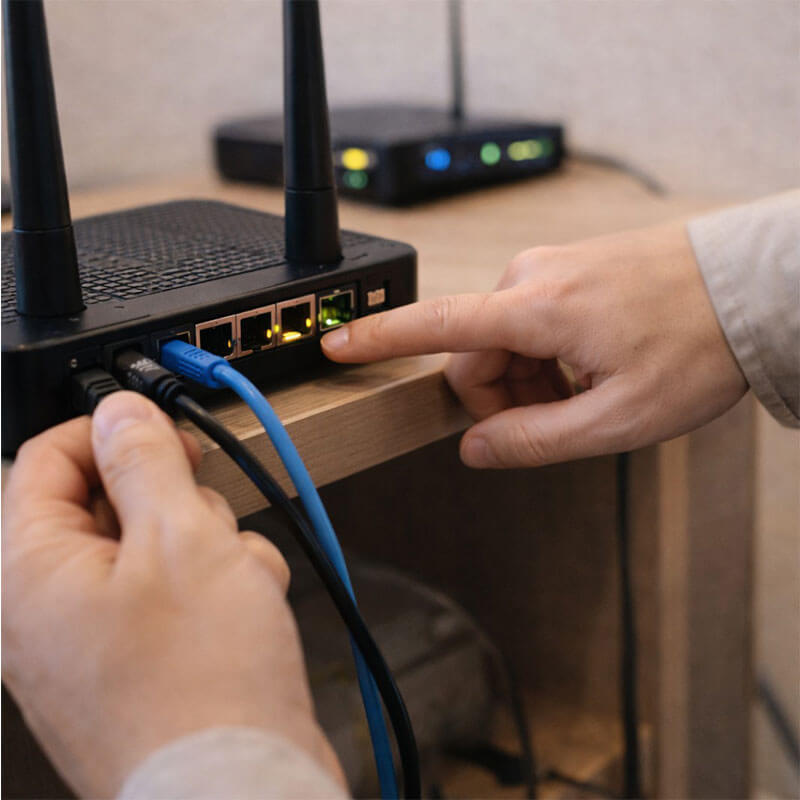 랜 케이블과 공유기 연결 상태를 확인하며 인터넷 장비를 점검하는 실내 장면