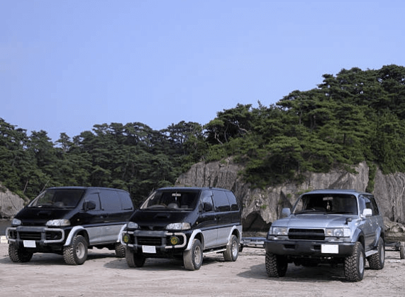 &ldquo;숲이 우거진 해안가에 주차된 검정색과 회색 오프로드 SUV 차량 3대&rdquo;