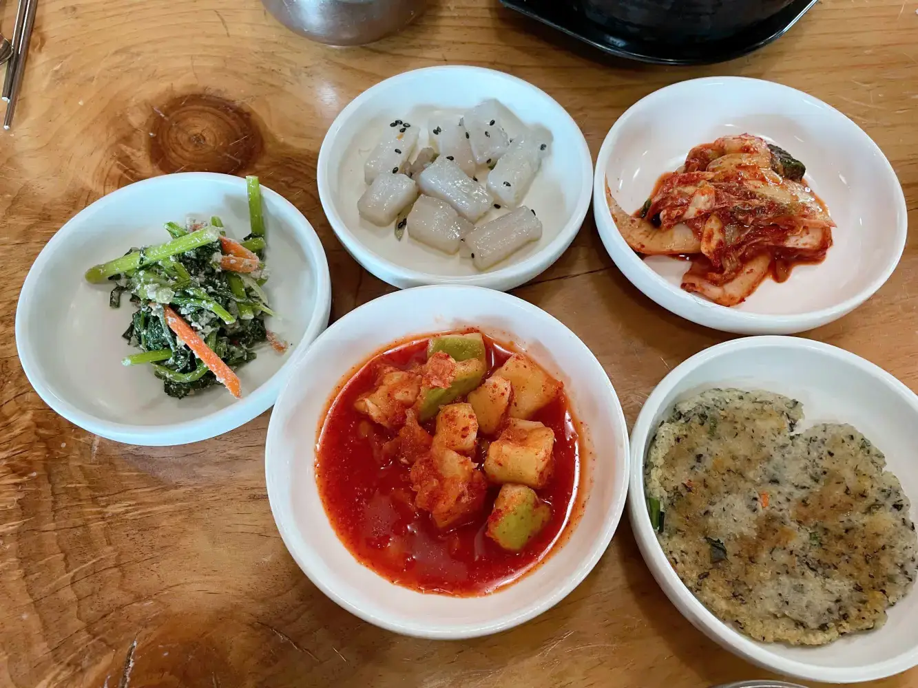 밑반찬 흰접시에 김치, 깍두기, 곤약볶음, 두부부침이 담겨져 있는 모습