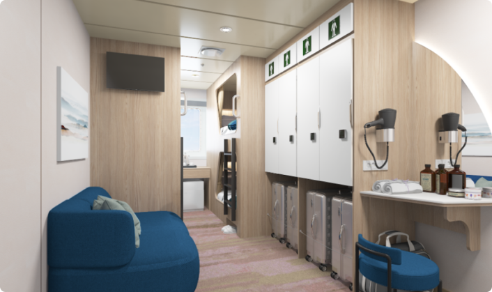 &ldquo;팬스타미라클호의 오션뷰 객실 내부. 좌측에는 파란색 소파와 액자가 있고, 우측에는 수납장이 줄지어 배치되어 있으며, 책상 위에는 드라이어와 어메니티가 놓여 있다. 안쪽에는 2층 침대와 창문이 있어 바깥 풍경을 볼 수 있다.&rdquo;