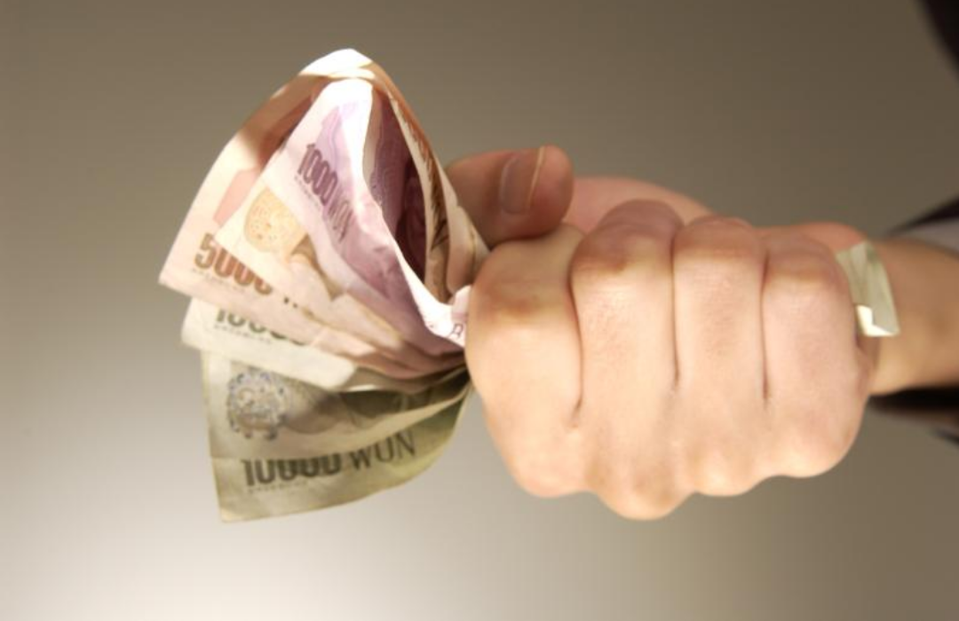 한 손으로 한국 지폐를 힘주어 쥐고 있는 모습.