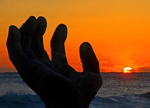 해가 떠오르는 빨간 하늘을 향해 손을 살짝 구루린 동상 옆모습