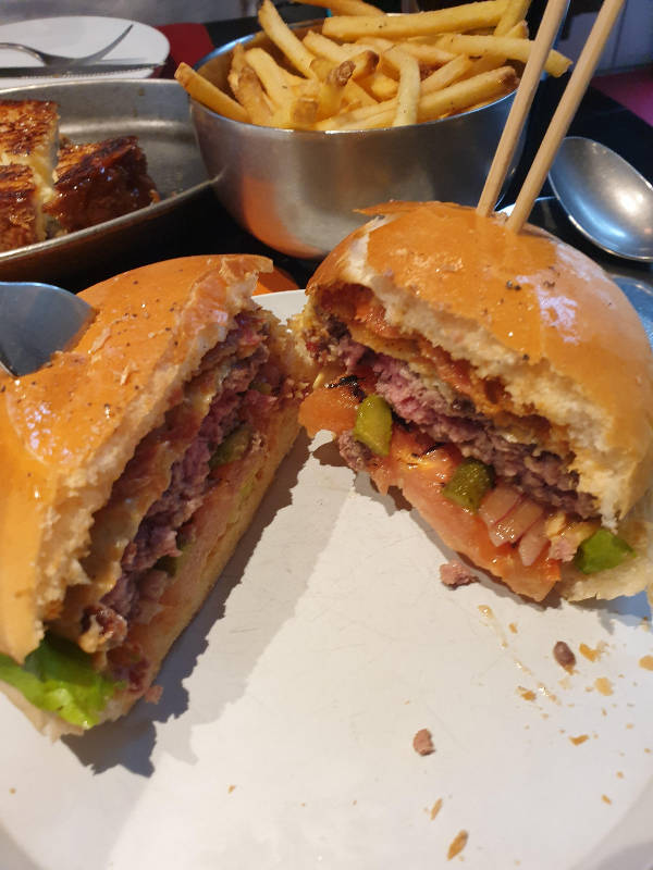 반으로 나뉜 햄버거. 패티가 분홍색이라 매력적이다. 토마토도 보인다.