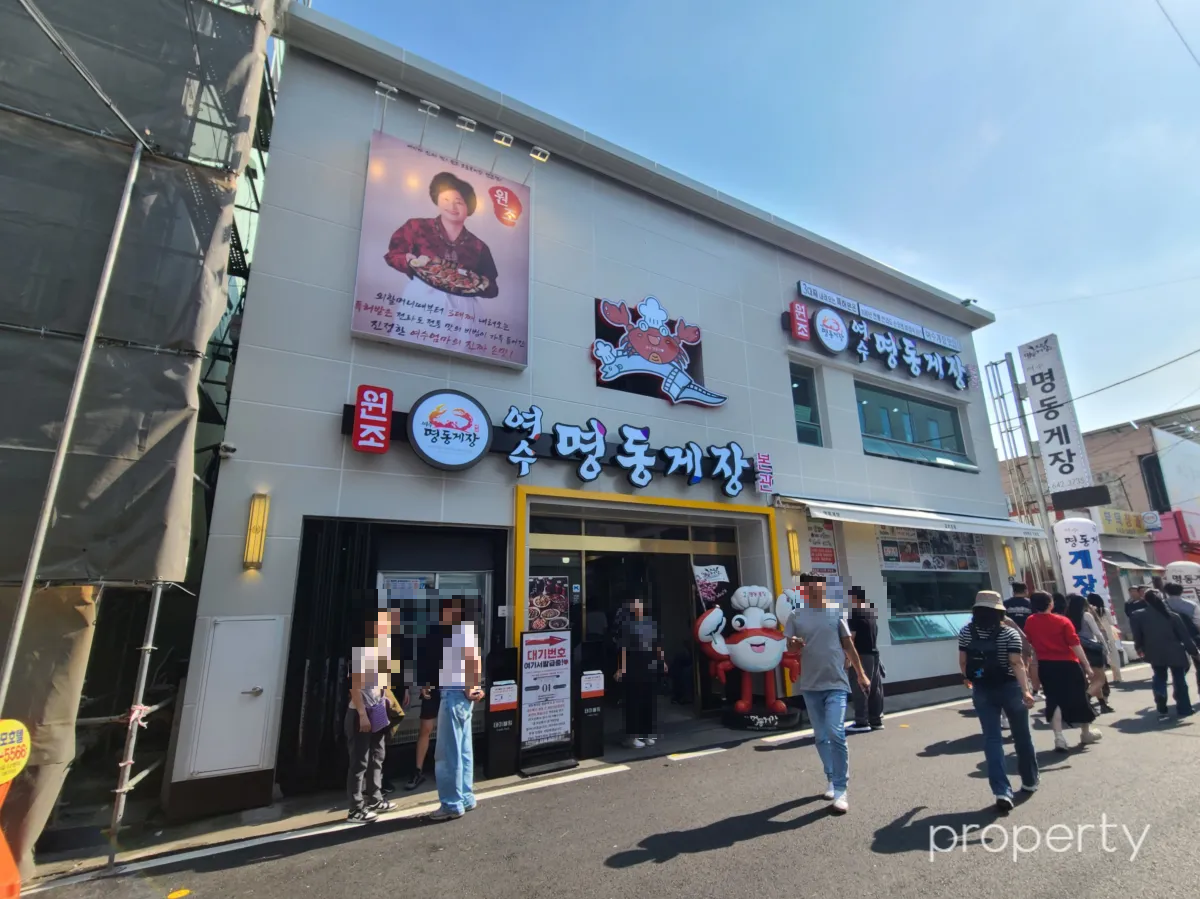 명동게장-본관-2층건물-문앞에-게인형-건물앞에-서있는-사람들-노란색-테두리-문-위에-명동게장간판