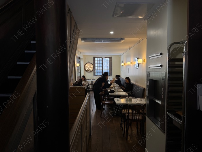 The cozy floor dining area of SAMSO restaurant with wooden floors, warm lighting, and diners enjoying their meal ❘ La salle à manger chaleureuse à l'étage du restaurant SAMSO