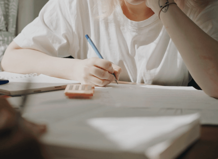 책상에 책과 노트를 펼쳐놓고 공부하는 사람