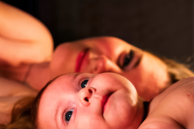 따뜻한 빛 속에서 엄마와 함께 누워있는 아기, 사랑스럽게 하늘을 바라보는 모습