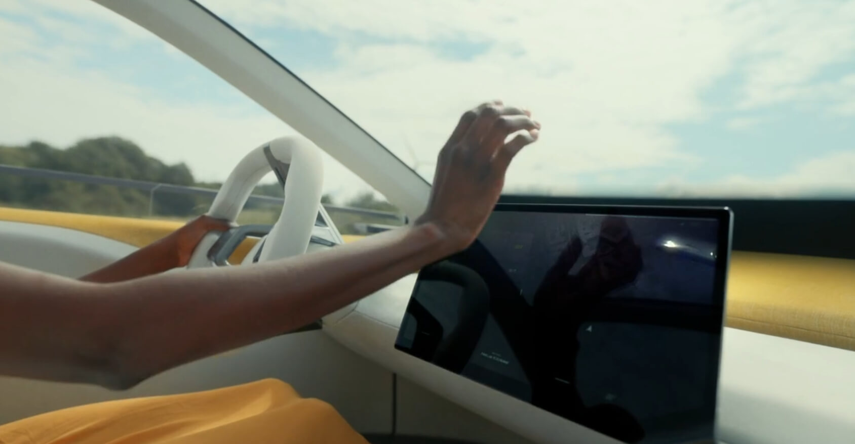 BMW Neue Klasse의 첨단 디지털 대시보드 클로즈업. 운전자가 터치스크린 디스플레이를 조작하는 모습과 함께 세련된 핸들이 눈에 띄며, 첨단 기술이 강조됩니다