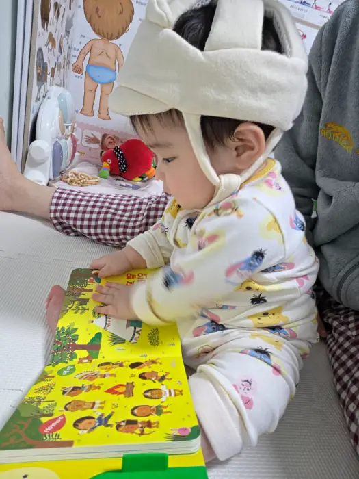 엄마 품에서 장난감가지고 노는 아이