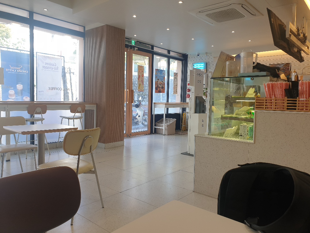 1층 내부에서 입구를 본 모습. 입구쪽 윈도우와 문 모두 유리다. 윈도우 뒤쪽에는 바형 테이블이 놓여있다.