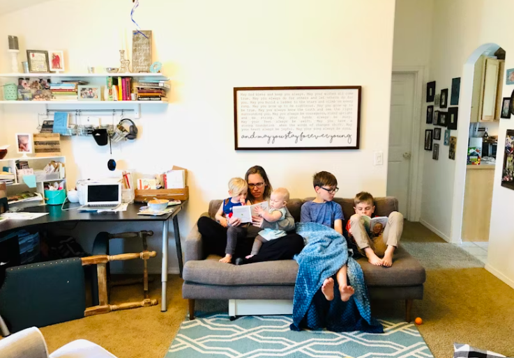 가족이 소파에 함께 앉아 책을 읽으며 따뜻한 시간을 보내는 모습