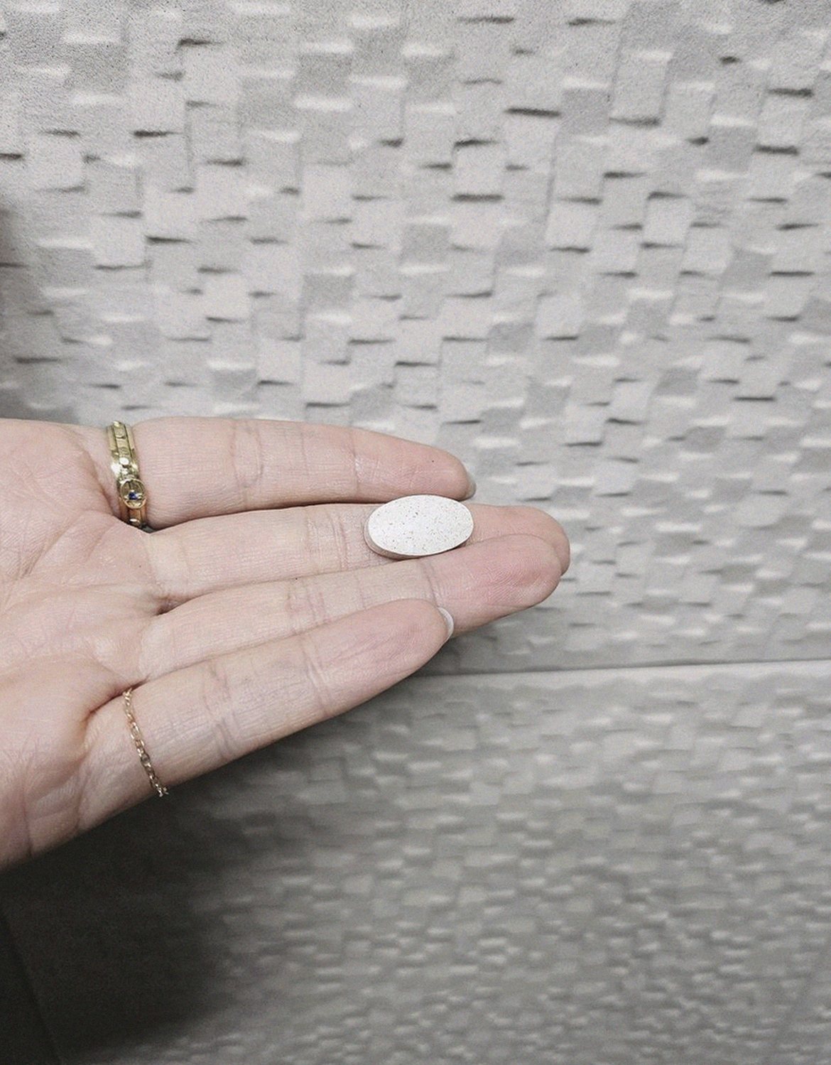 Korean Asian man in 40s holding supplement tablet showing size