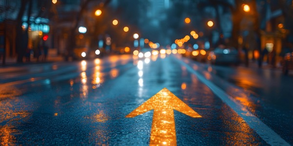 밤거리 젖은 아스팔트 위에 빛나는 화살표가 앞 방향을 가리키는 이미지