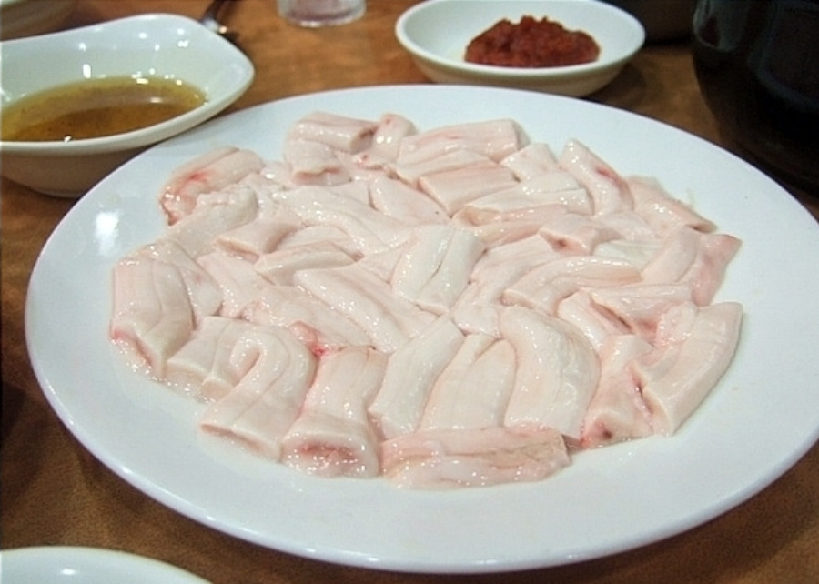야생에서 채취를 한 소의 뼈속에서 나온 골수를 깨끗하게 세척한 후에 동그랗고 하얀 그릇에 가득 담아둔 것을 나무테이블 위에 놓아두고 그 옆에 기름소금장과 된장을 두고 찍은 사진
