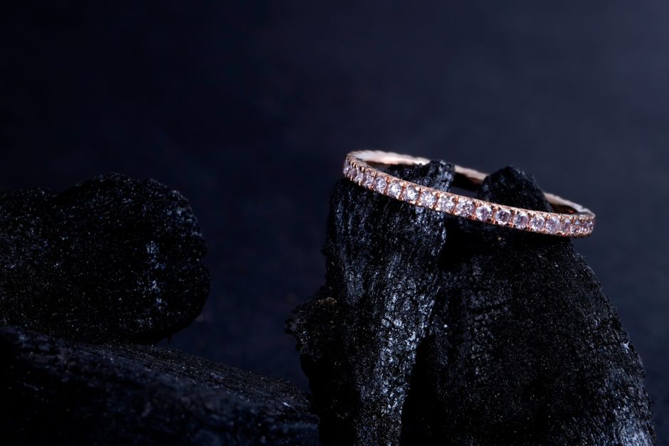 A close-up shot of a sparkling diamond ring elegantly placed on a textured black stone surface.