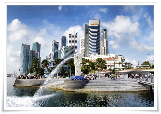 뒤로 높은 빌딩숲을 배경으로, 사자머리의 머라이언이 입에서 강으로 물을 힘차게 뿜어내는 사진