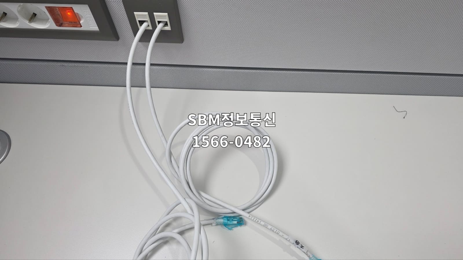 사무실 책상 위에 향후 PC 위치 변경에 대비해 여유 길이로 둥글게 말아둔 흰색 랜케이블.