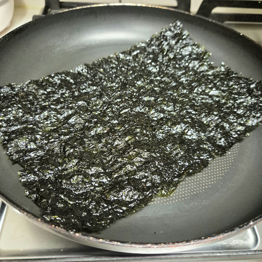 눅눅해진 김 한 장을 기름 없는 프라이팬에 약불로 데우는 모습