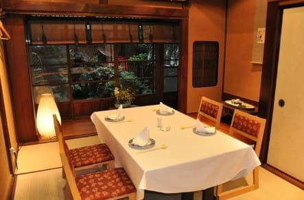 식탁에 흰색 식탁보가 있고 의자 4개가 놓여있다