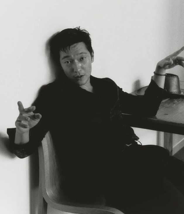 검은 옷을 입고 앉아 손짓하는 손석구