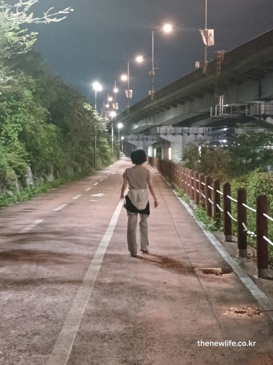 강변 도로에서 혼자 만 보 걷기 운동 중인 여성